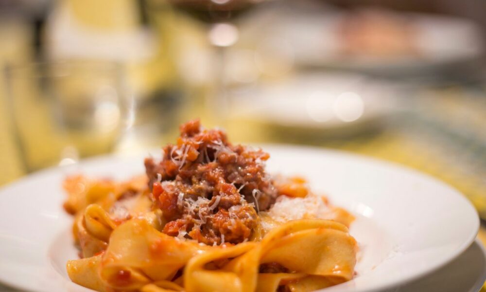 Authentic homemade Tagliatelle alla Bolognese with Romagnola meat sauce, served on a traditional plate.