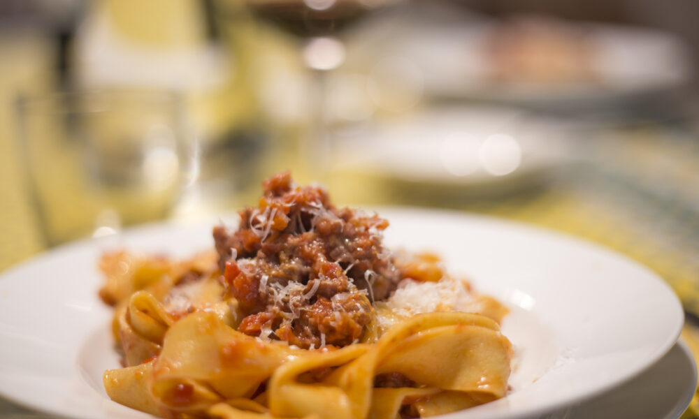 Authentic homemade Tagliatelle alla Bolognese with Romagnola meat sauce, served on a traditional plate.