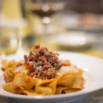 Authentic homemade Tagliatelle alla Bolognese with Romagnola meat sauce, served on a traditional plate.